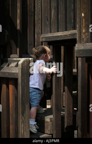 Toddler girl playing on wood playground. Stock Photo