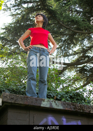 young woman with attitude standing on wall covered in urban graffiti Stock Photo
