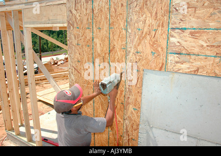 Latin American Mexican work crew building wooden stick built house home cutting measure nailing on hot day in Georgia for family home residence Stock Photo