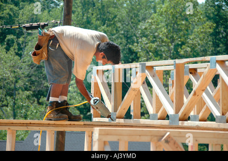 Latin American Mexican work crew building wooden stick built house home cutting measure nailing on hot day in Georgia for family home residence Stock Photo