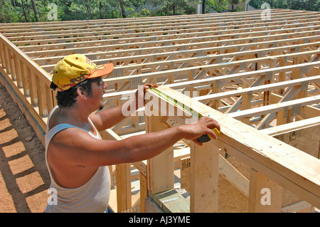 Latin American Mexican work crew building wooden stick built house home cutting measure nailing on hot day in Georgia for family home residence Stock Photo