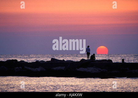 Couple on Breakwater Silhouetted Against Lake Michigan Sunset Holland Michigan Stock Photo