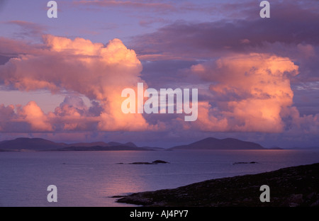 Towering clouds over South Harris and North Uist are painted pink by the evening light Stock Photo