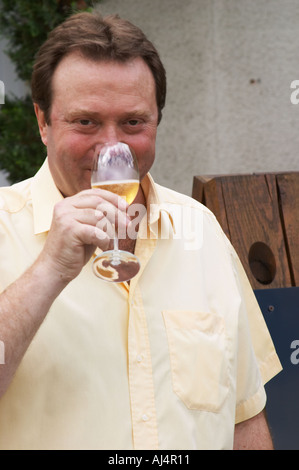 Claude Giraud, owner and winemaker, tasting a glass of his wine in the court yard in front of his house Champagne house Maison Giraud-Hemart, also called Champagne Henri Giraud, Ay, Vallée de la Marne, Champagne, Marne, Ardennes, France Stock Photo