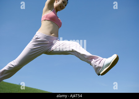 Young woman leaping in field Stock Photo