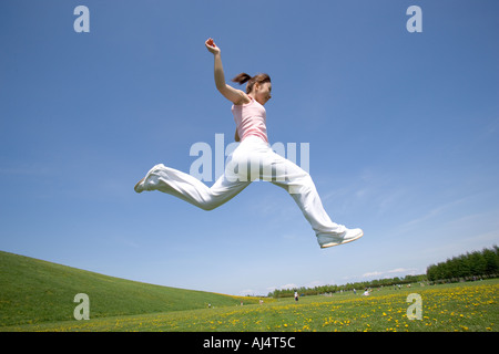 Young woman leaping in field Stock Photo