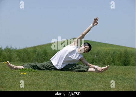 Young man doing the splits in field Stock Photo