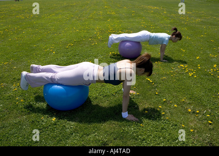 Two young Woman doing push ups with their legs on fitness balls Stock Photo