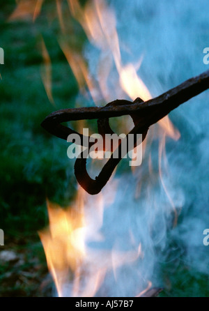 Heating branding iron in campfire Stock Photo