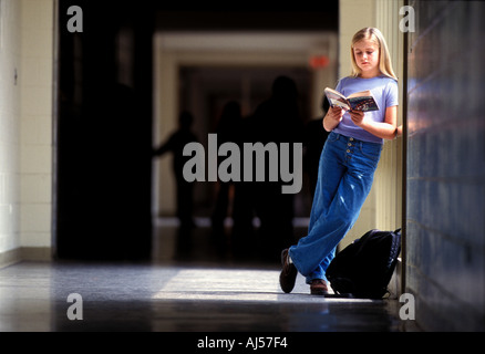 Female Caucasian student reading book in middle school hallwayThis Stock Photo