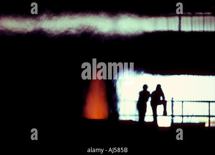 Silhouette workmen checking smelting flame in steel mill Stock Photo