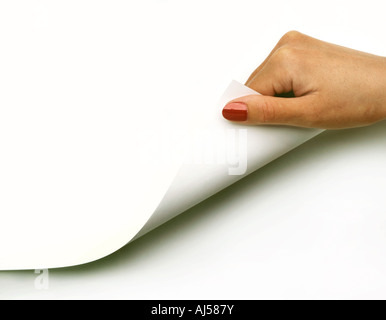 WOMANS HAND TURNING THE CORNER OF A BLANK PIECE OF PAPER OR PAGE Stock Photo