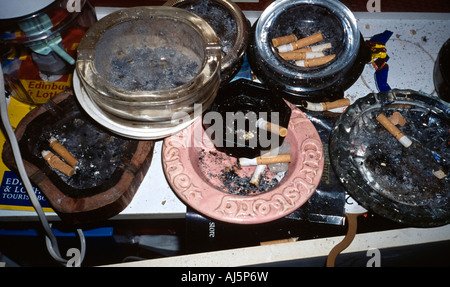 Dirty ashtrays piled up on a table. Stock Photo