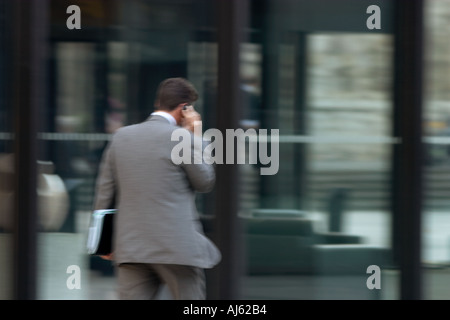 businessman walking into foyer of offices while talking on mobile phone