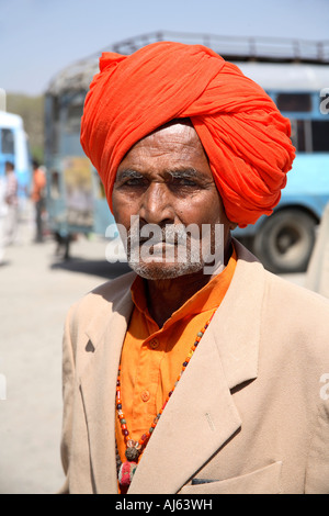 Portrait of sorrowful Indian man at bus station wearing orange turban and saffron coloured shirt, Junagadh, Saurashtra, India Stock Photo