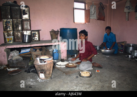 Young Indian boys making chapati in traditional, archaic kitchen, Khavda Village, Kutch district, Gujarat, India Stock Photo