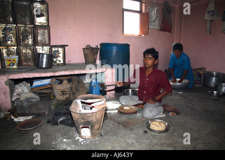 Young Indian boys making chapati in traditional, archaic kitchen, Khavda Village, Kutch district, Gujarat, India Stock Photo