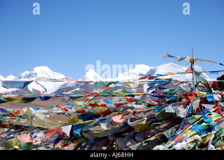 Prayer flags frame the vast Himalayan mountain range which is clearly seen from the top of the 5200m Shung La pass in Tibet Stock Photo