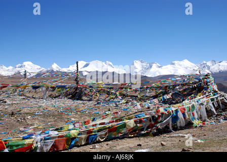 Prayer flags frame the vast Himalayan mountain range which is clearly seen from the top of the 5200m Shung La pass in Tibet Stock Photo