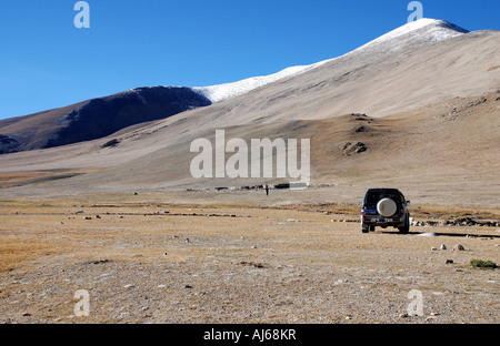 The snowy peaks of the high Himalayas are seen above the barren hills of the Tibetan plateau Stock Photo