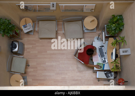 Looking down from a birds eye perspective on a small office scene Here a man works while on the internet Stock Photo