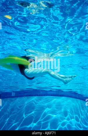 Underwater view of woman in pool floating in life ring Model Released Image Stock Photo