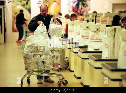 A man loading a shopping trolley with shopping bags in Sainsbury's supermarket Stock Photo