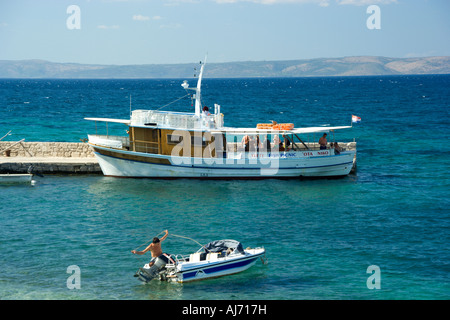 Cruise ship and fisherman in his boat in Duba Peljeska port Croatia Stock Photo