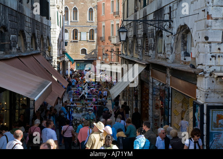 A narrow shopping street near Piazza san Marco full of tourists shopping from shops and market stalls Stock Photo
