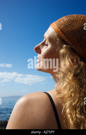 Profile of Caucasian mid adult woman with wavy hair and head scarf at coast Stock Photo