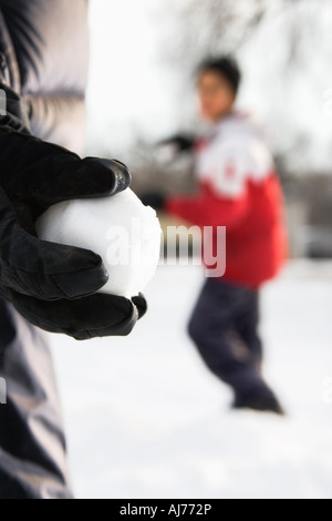 Boy holding snowball ready to throw at boy in background Stock Photo