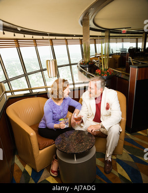 Mature Caucasian couple sitting in bar lounge having drinks and talking Stock Photo