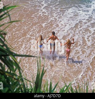 young man and two women running in surf Acapulco Mexico Stock Photo