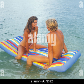 young romantic couple sitting on inflatable raft at beach Stock Photo