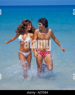 young couple running in surf at beach Stock Photo