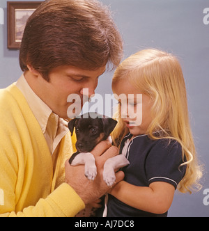 father with young daughter playing with puppy Stock Photo