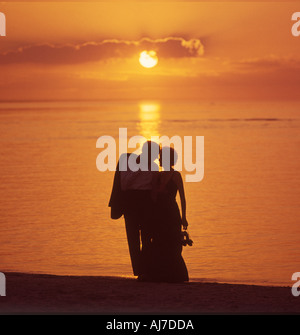 romantic couple walking on beach at sunset Stock Photo