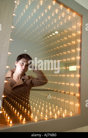 Woman looking at reflection in illuminated mirror Stock Photo