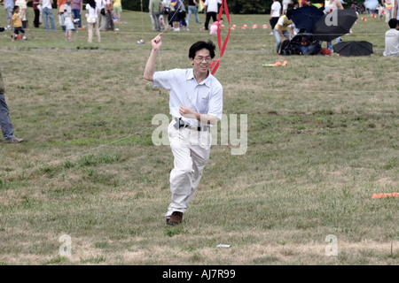Asian man running with Kite at Kite Festival in Liberty State Park Jersey City NJ Stock Photo