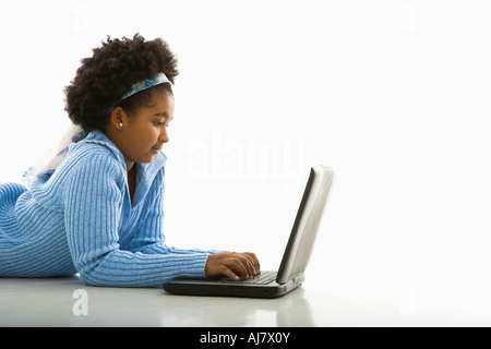 Side view of African American girl lying on floor using laptop Stock Photo