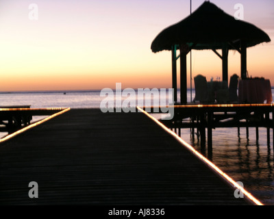 Lights on wooden boardwalk at dusk by sandy beach & pagoda, Mauritius Stock Photo