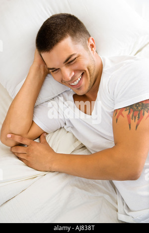 High angle view of handsome Caucasian mid adult man lying in bed smiling Stock Photo