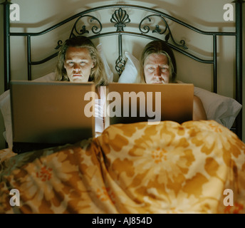 couple working on laptop computers in bed at night Stock Photo
