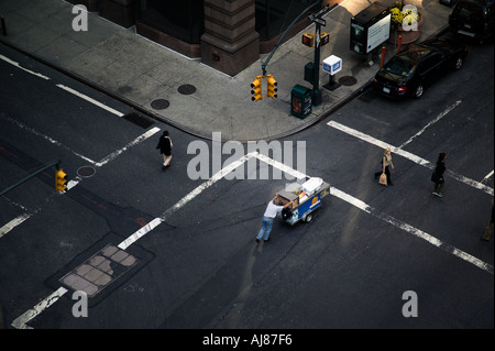 Man pushing food vending cart through intersection of Eighth Avenue at 48th Street in Midtown Manhattan New York NY Stock Photo