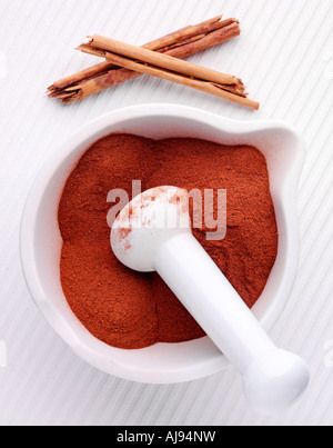 CINNAMON STICKS WITH GROUND CINNAMON IN PESTLE AND MORTAR Stock Photo