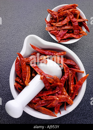 WHOLE RED DRIED CHILLIES IN PESTLE AND MORTAR Stock Photo