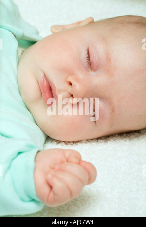 Baby asleep and dressed in green jumpsuit Stock Photo