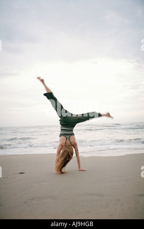 Young woman doing cartwheel on beach Stock Photo