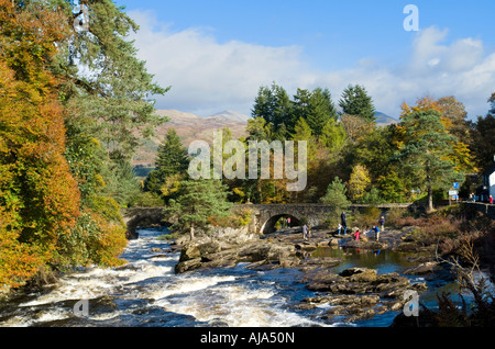 Multiple small waterfalls at the Falls of Dochart on River Dochart at Killin Scotland with the River Dochart Bridge on a sunny autumn day Stock Photo