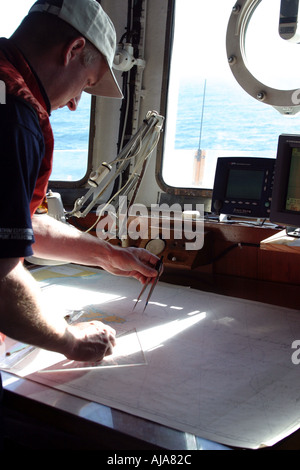 Navigator standing over charts working out the ships course Stock Photo